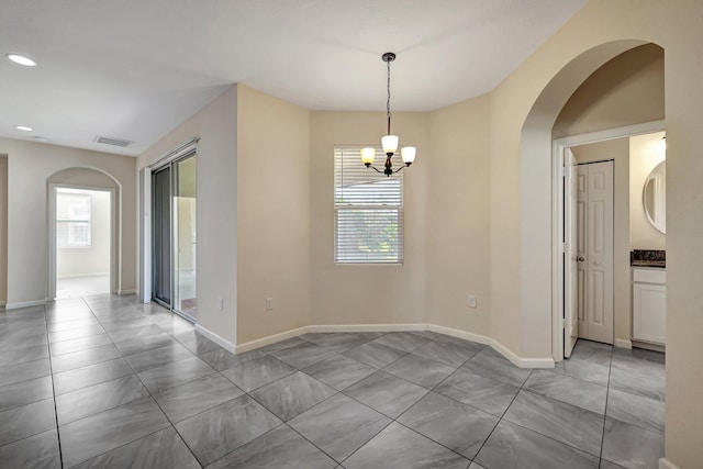 unfurnished room featuring a wealth of natural light and a notable chandelier