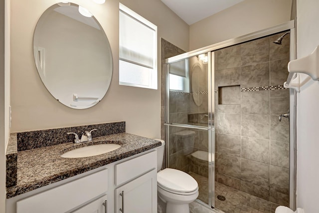 bathroom with walk in shower, vanity, and toilet