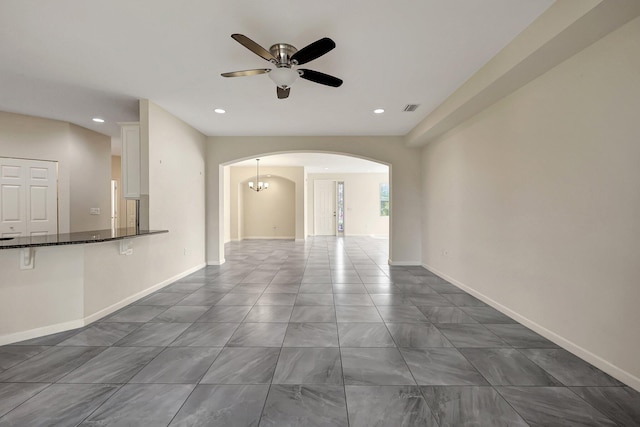 unfurnished living room with ceiling fan with notable chandelier