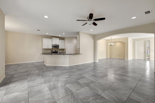 unfurnished living room featuring ceiling fan with notable chandelier and sink