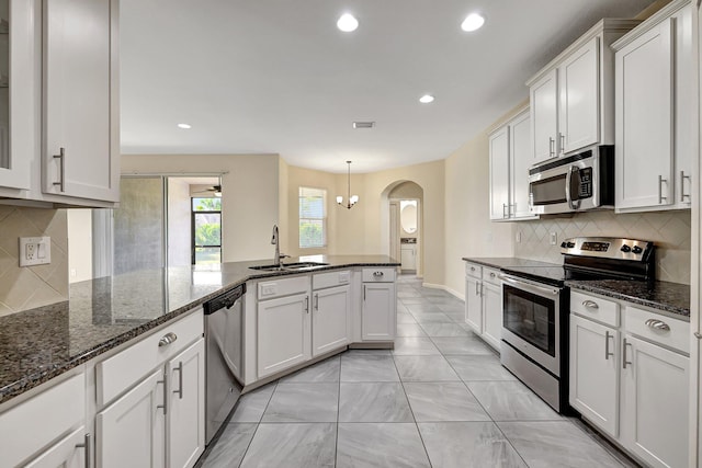 kitchen featuring stainless steel appliances, sink, decorative light fixtures, white cabinetry, and backsplash