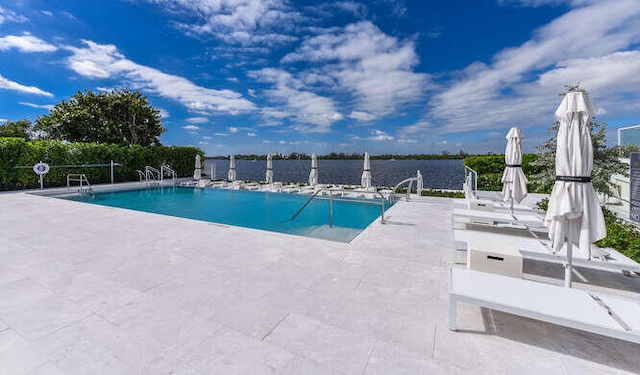 view of pool featuring a water view and a patio area