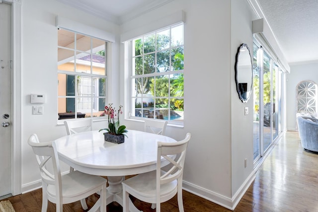 dining area with a textured ceiling, ornamental molding, and wood-type flooring