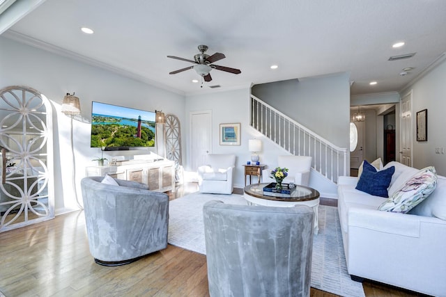 living room with wood-type flooring, ornamental molding, and ceiling fan