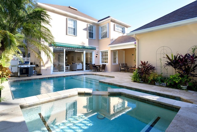 rear view of house featuring a patio and a swimming pool with hot tub