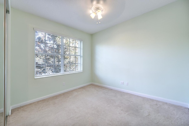 carpeted spare room with ceiling fan