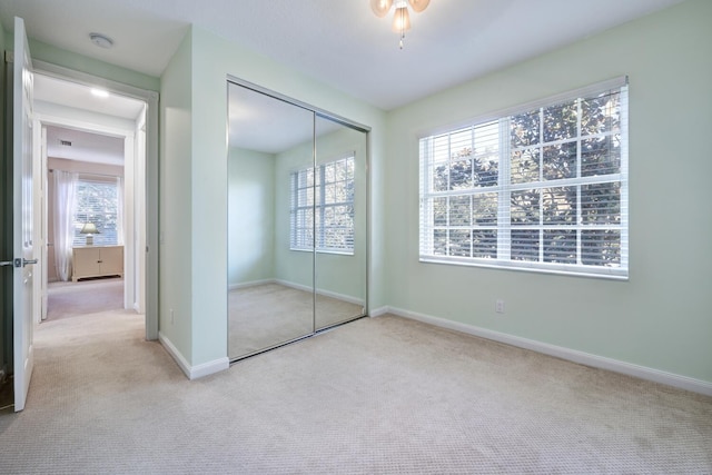 unfurnished bedroom featuring light colored carpet and a closet