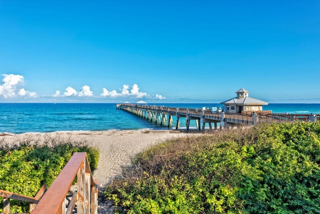 view of dock featuring a beach view and a water view