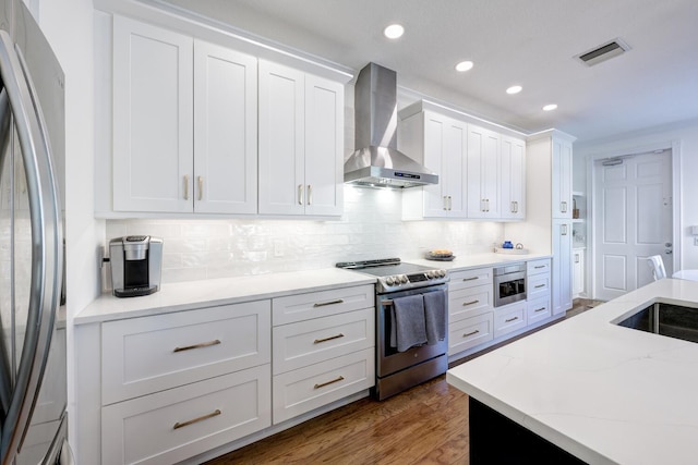 kitchen featuring stainless steel appliances, wall chimney range hood, white cabinetry, and dark wood-type flooring