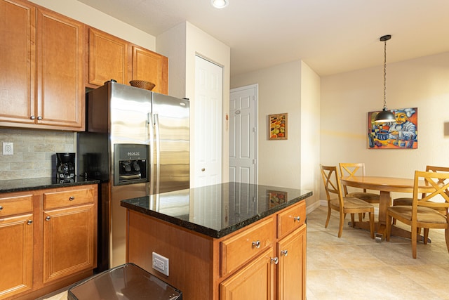 kitchen with backsplash, hanging light fixtures, stainless steel fridge, dark stone countertops, and light tile patterned flooring