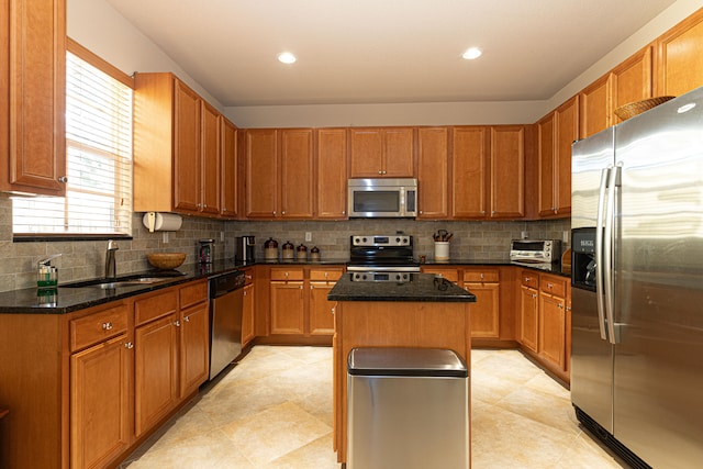 kitchen with a center island, sink, decorative backsplash, dark stone countertops, and stainless steel appliances