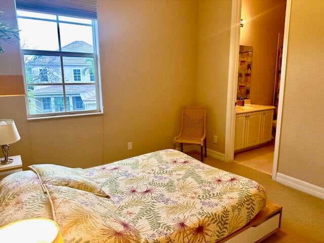 bedroom featuring light carpet and ensuite bath