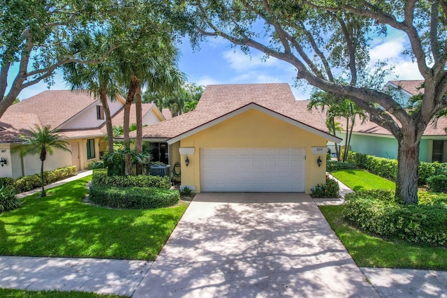 single story home featuring cooling unit, a garage, and a front yard