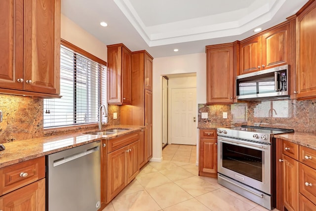 kitchen featuring decorative backsplash, stainless steel appliances, light stone counters, and sink