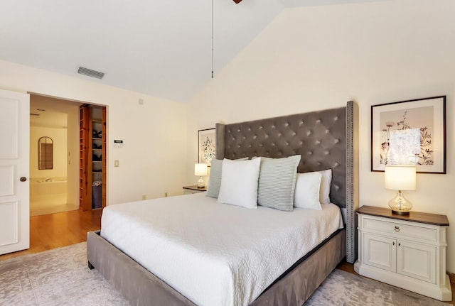 bedroom with light hardwood / wood-style floors, high vaulted ceiling, and ensuite bath