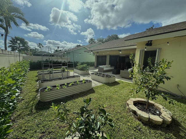 back of property with a lawn, an outdoor living space with a fire pit, and a patio