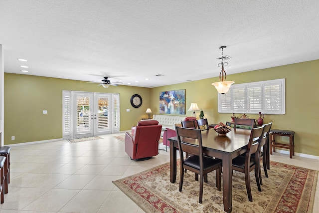 tiled dining space with ceiling fan, a textured ceiling, and french doors