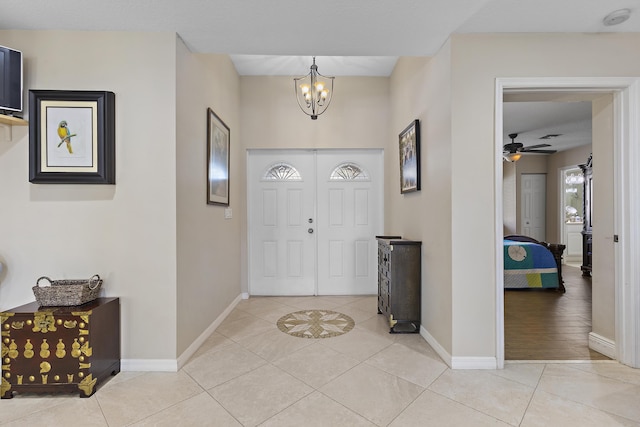 tiled foyer with ceiling fan with notable chandelier