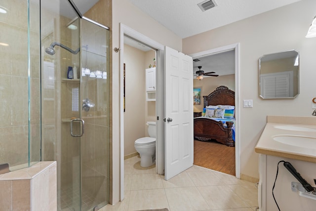 bathroom with ceiling fan, tile patterned floors, a textured ceiling, toilet, and a shower with door