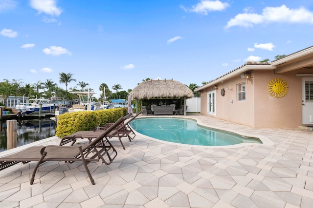 view of swimming pool featuring a gazebo, a patio area, a water view, and a dock