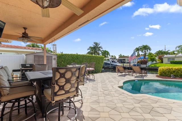 view of swimming pool with a patio area, ceiling fan, and a storage shed