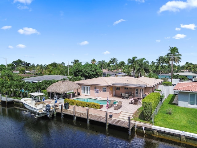 back of property with a yard, a water view, and a patio area