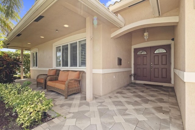 view of exterior entry with a patio and outdoor lounge area