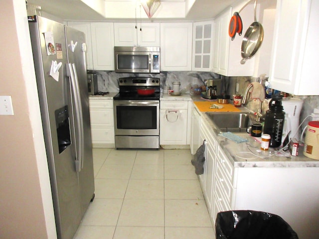 kitchen with white cabinets, sink, decorative backsplash, light tile patterned flooring, and stainless steel appliances