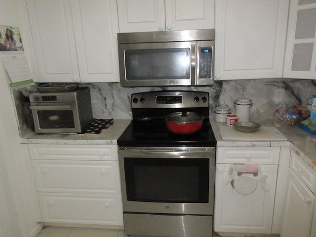 kitchen featuring backsplash, white cabinetry, and appliances with stainless steel finishes