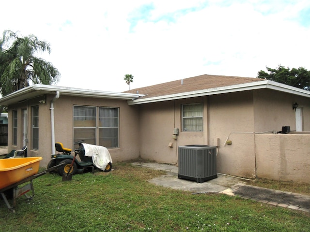 back of property featuring central air condition unit and a yard