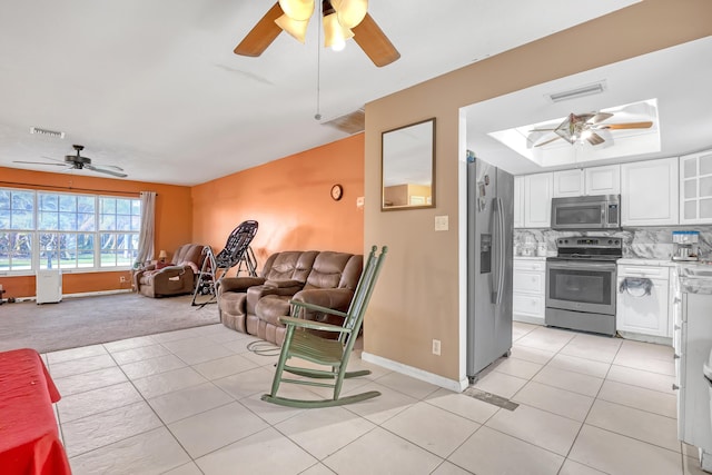 tiled living room featuring ceiling fan and a skylight