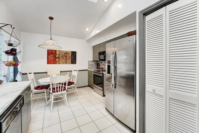 kitchen with lofted ceiling, backsplash, light tile patterned floors, decorative light fixtures, and stainless steel appliances