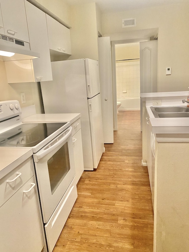 kitchen with white appliances, exhaust hood, sink, light hardwood / wood-style floors, and white cabinetry