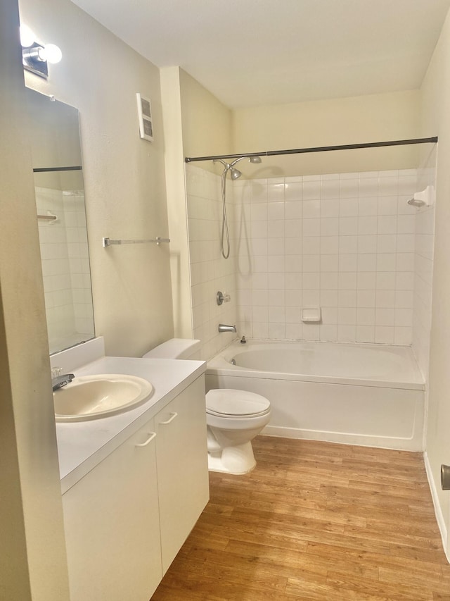 full bathroom with hardwood / wood-style flooring, vanity, toilet, and tiled shower / bath