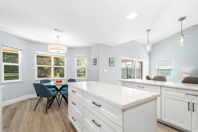 kitchen featuring white cabinets, decorative light fixtures, and a healthy amount of sunlight