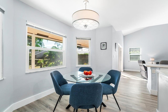 dining room with light hardwood / wood-style flooring and lofted ceiling