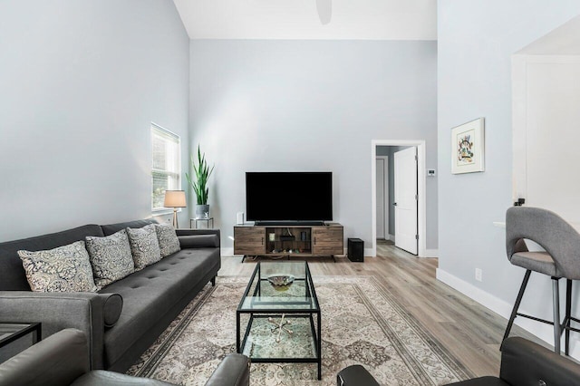 living room with light wood-type flooring and high vaulted ceiling