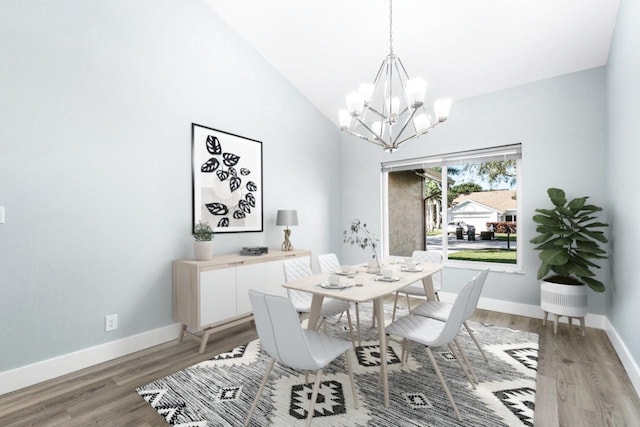 dining space featuring hardwood / wood-style flooring, vaulted ceiling, and an inviting chandelier