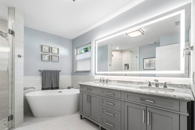 bathroom featuring shower with separate bathtub, vanity, and tile walls