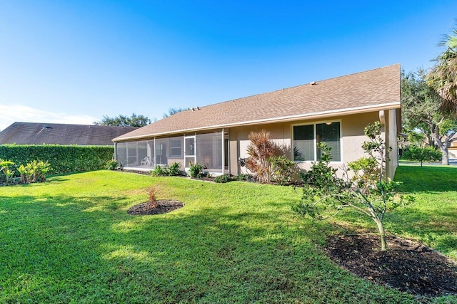 rear view of house with a lawn and a sunroom