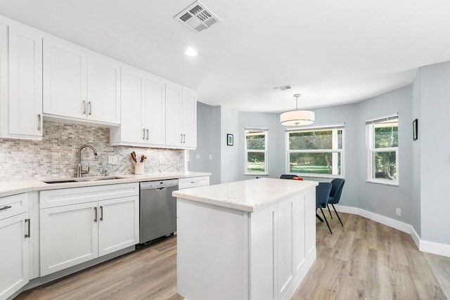 kitchen featuring white cabinets, sink, stainless steel dishwasher, decorative light fixtures, and light hardwood / wood-style floors