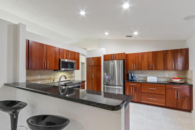 kitchen with kitchen peninsula, backsplash, appliances with stainless steel finishes, and vaulted ceiling