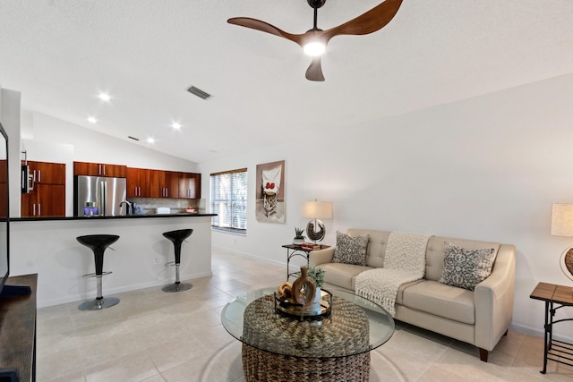 living room featuring ceiling fan, sink, light tile patterned floors, and vaulted ceiling