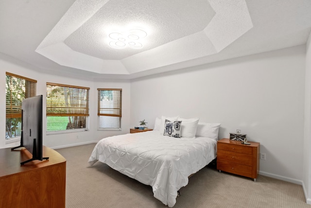 carpeted bedroom with a textured ceiling and a tray ceiling