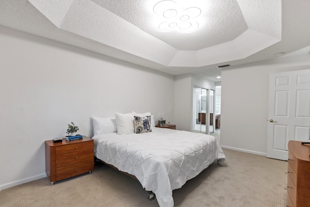 carpeted bedroom with a raised ceiling and a textured ceiling