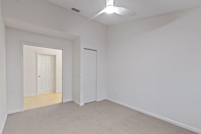 unfurnished bedroom featuring ceiling fan, a closet, and light carpet