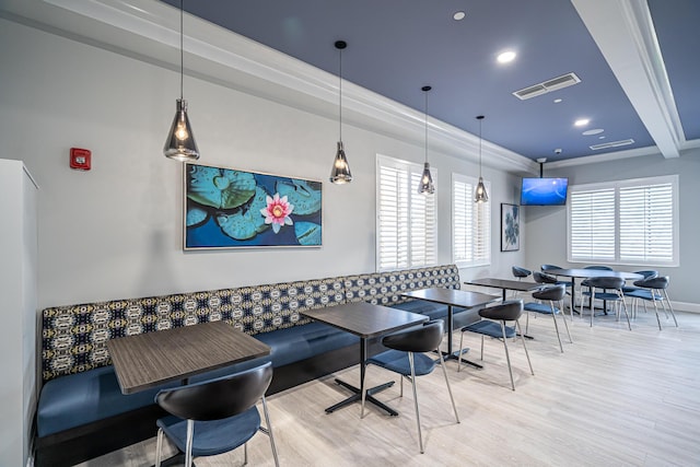 dining room with beamed ceiling, light wood-type flooring, crown molding, and a healthy amount of sunlight