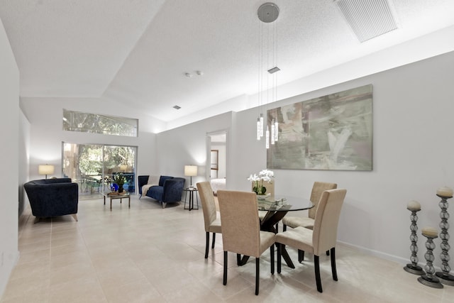 tiled dining room featuring a textured ceiling and lofted ceiling