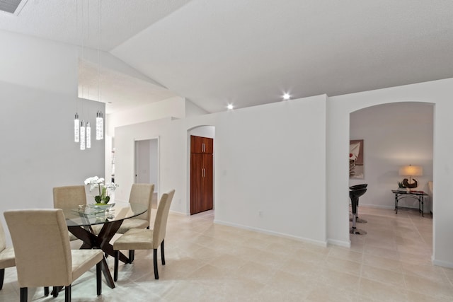 dining room featuring light tile patterned flooring, lofted ceiling, and a textured ceiling