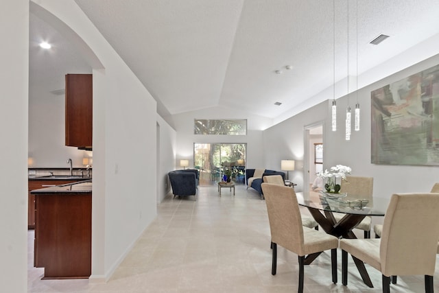 tiled dining room featuring a textured ceiling, vaulted ceiling, and sink